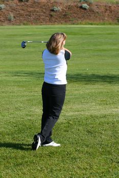 Blond female golfer playing a shot from the fairway
