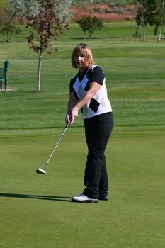 Blond female golfer putting on the green