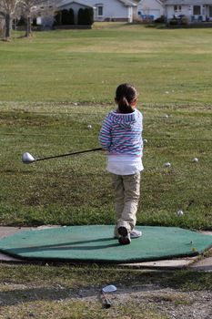 Young female golfer practising on the driving range