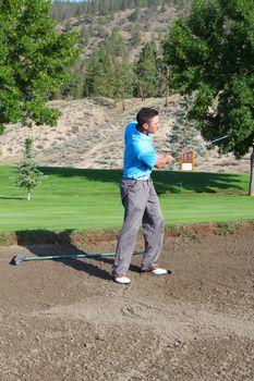 Young male golfer hitting a shot from the bunker