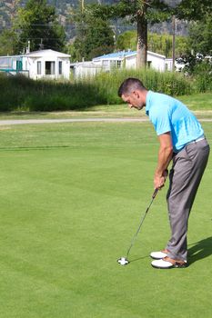 Young golfer preparing for his putt on the green
