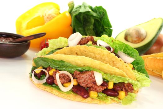 Mexican tacos with ground beef, lettuce, red kidney beans and corn on a white background