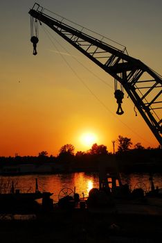 silhouettes on crane in port of Sava river over orange sunset in Belgrade, Serbia