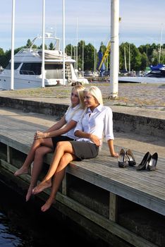 Two girls resting on the pier by the sea