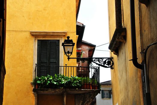 street lamp on building wall and balcony on yellow building facade, architecture details of Verona, Italy