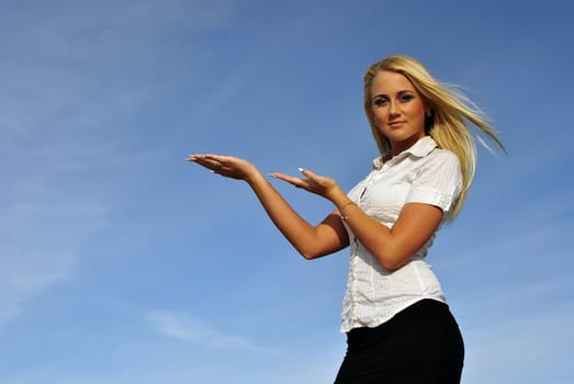 Blonde girl in a white shirt against the sky. Ideally suited for advertising. Space for text
