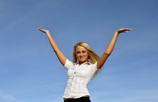 Blonde girl in a white shirt against the sky. Ideally suited for advertising. Space for text