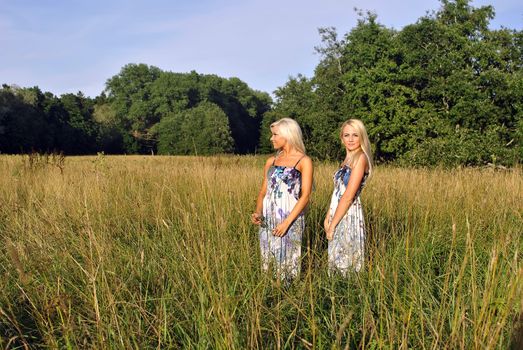 Two girls in the grass near the forest