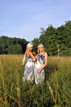 Two girls in the grass near the forest