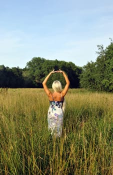 Blonde girl alone in field. From the back. Freedom.