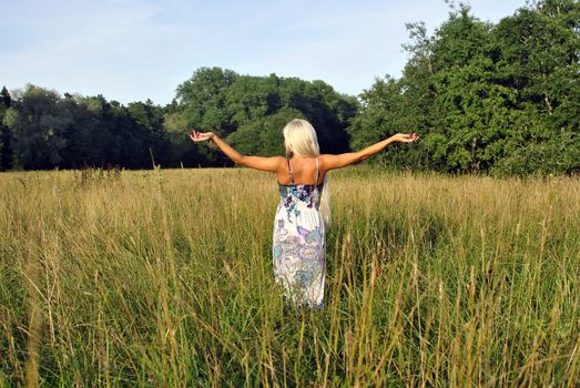 Blonde girl alone in field. From the back. Freedom.