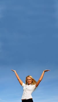 Blonde girl with hands up in a white shirt against the sky. Ideally suited for advertising. Space for text