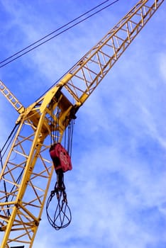 Partial view of a yellow construction crane against blue sky

