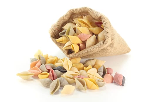 a handful of colored pasta in a bag on white background