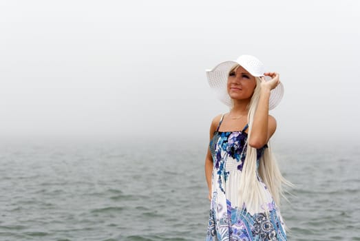 Girl in hat standing in the misty sea