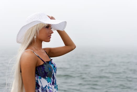Girl in hat standing in the misty sea