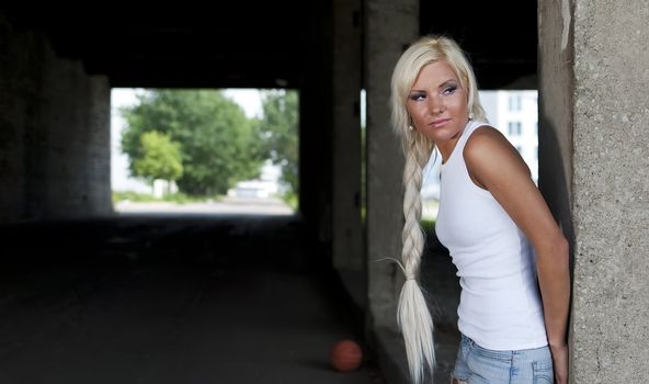 athletic girl in denim shorts and white T-shirt standing at the pillar