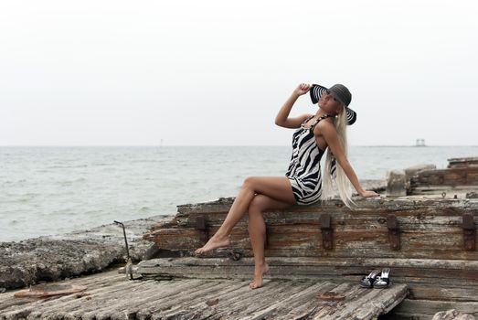 girl in a hat sitting on a broken ship at sea