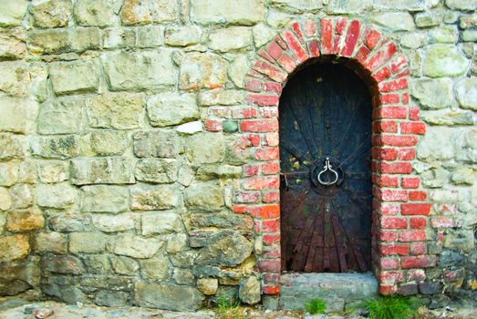 an old rusty door in the wall of the monastery