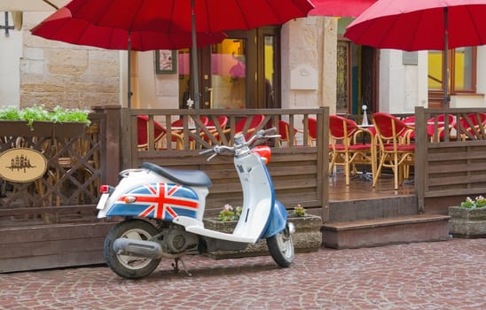 old scooter decorated with the British flag in front of cafe
