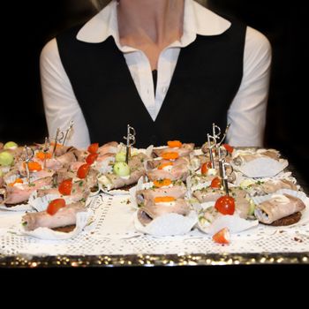 Waitress serving finger food. In the foreground, the tray can be seen with the appetizers. - Textile-square