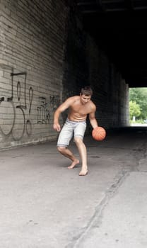 Male playing street basketball alone
