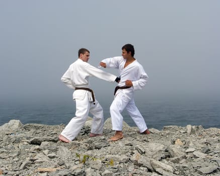 two karateka fight on the banks of the misty sea