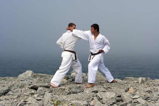 two karateka fight on the banks of the misty sea