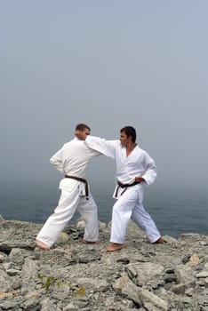 two karateka fight on the banks of the misty sea