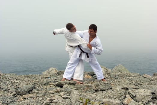 two karateka fight on the banks of the misty sea