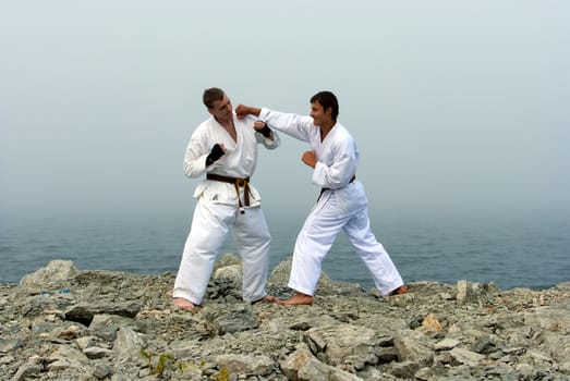 two karateka fight on the banks of the misty sea