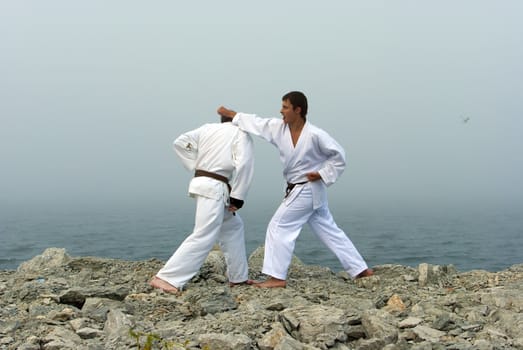 two karateka fight on the banks of the misty sea