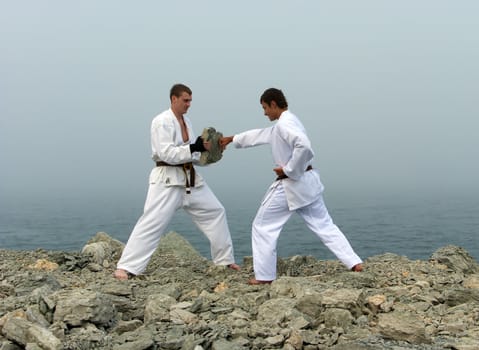 two karateka fight on the banks of the misty sea