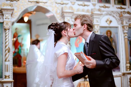 The bride and groom kiss at the ceremony in the church.