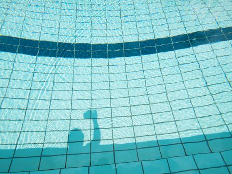 Shadow of a photographer taking pictures with his camera by the pool