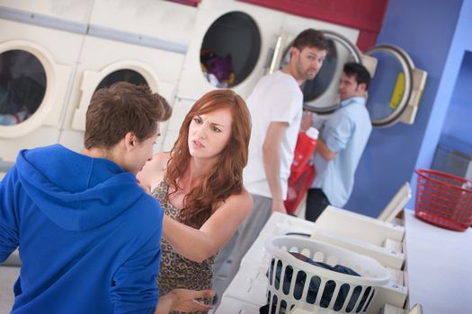 Beautiful young Caucasian lady argues with boyfriend in laundromat