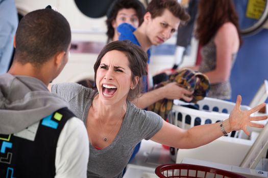 Frustrated young woman yells at a man in the laundromat