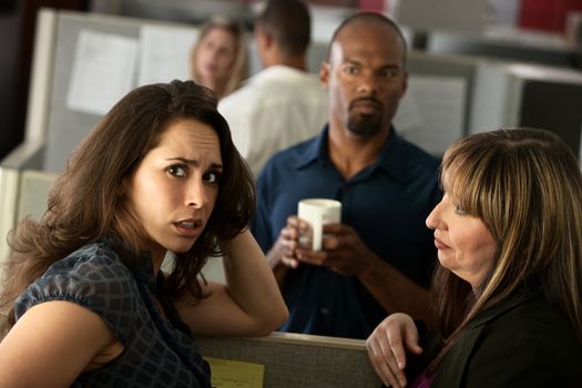 Worried woman office worker chats with friends at her cubicle