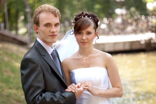 young bride and groom embracing each other, are happy in the park