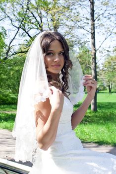 beautiful young bride sitting on a park bench
