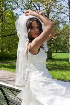 beautiful young bride sitting on a park bench