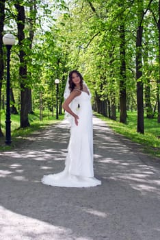 young bride standing in an alley in the park