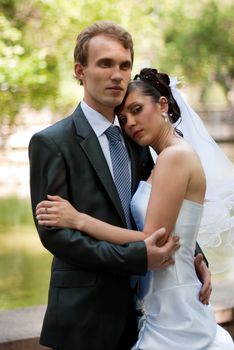 young married couple, arm in arm on the background of a beautiful and blooming garden