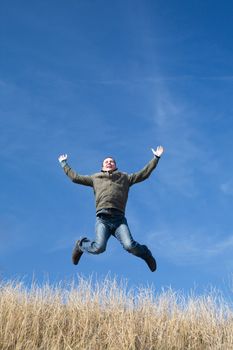 successful and happy man running and jumping in the yellow field