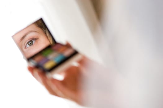 small looking-glass with cosmetics in the hand of the girl