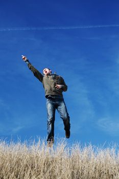 successful and happy man running and jumping in the yellow field