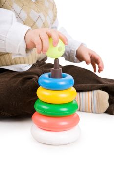 The toddler boy plays developing game. Color pyramidion.