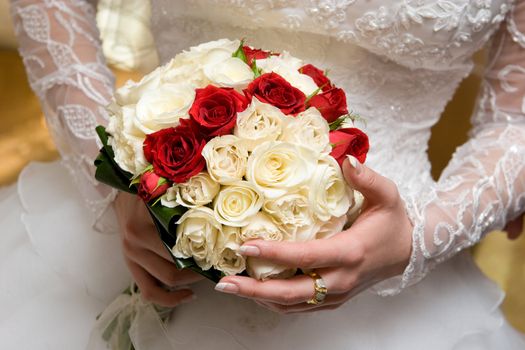 white and red rose bouquet in the hands of the bride