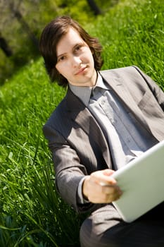 portrait of businessman with notebook on green grass field