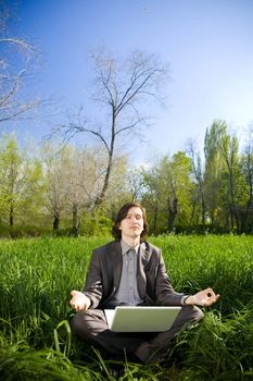 a young business man with a laptop relax on the grass field